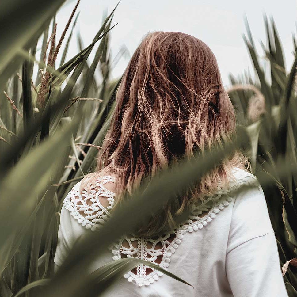 A woman walking through stalks of corn