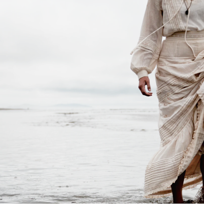 A woman in a dress walking along the beach
