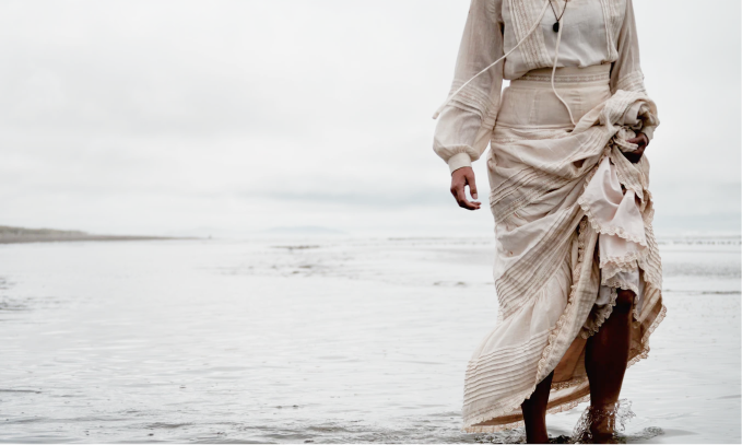 A woman in a dress walking along the beach