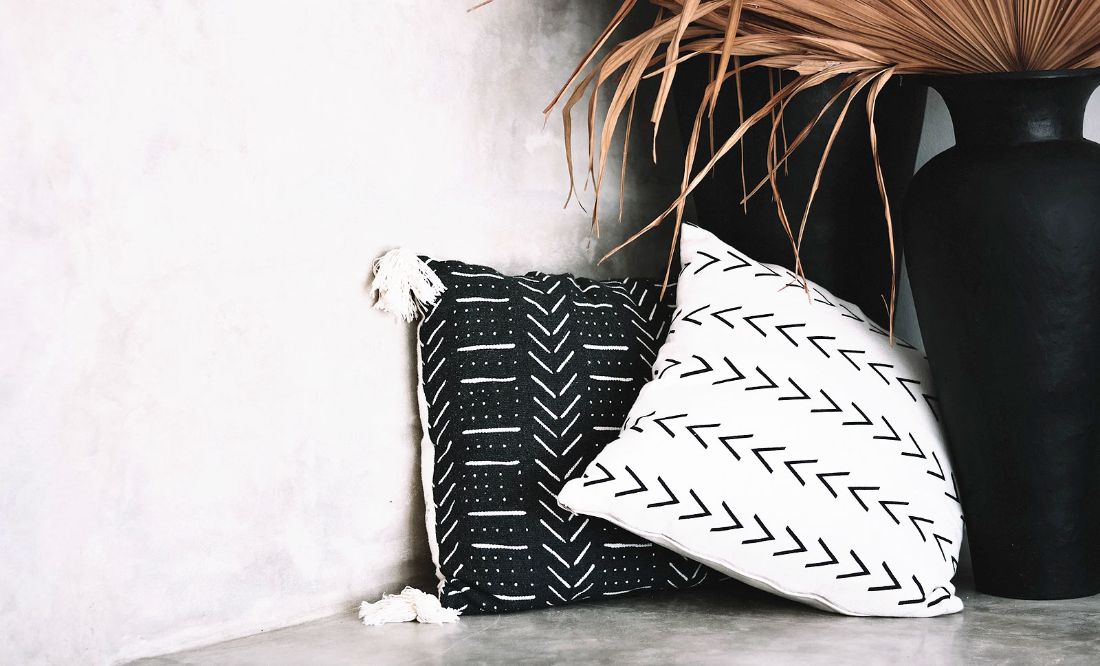 Patterned pillows next to a black vase