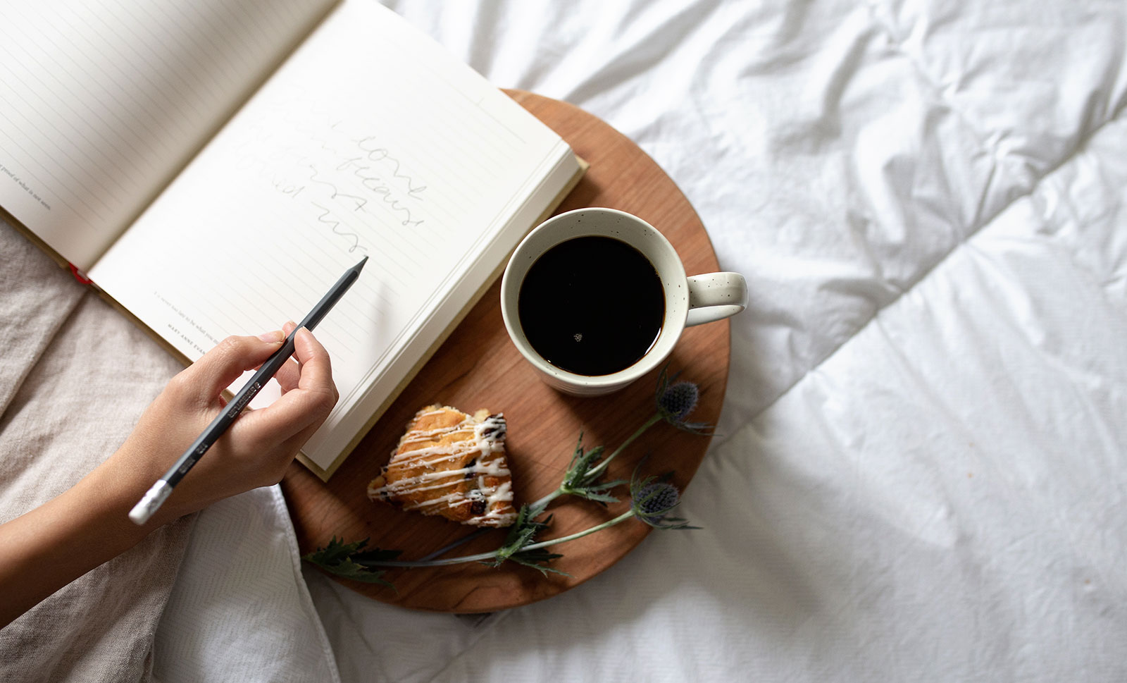 An open journal next to a cup of coffee and pastry