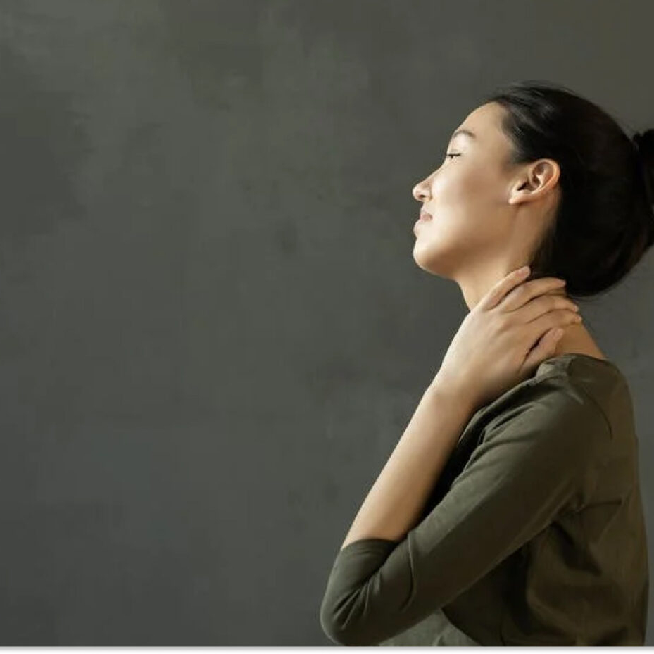 A woman placing a hand on the side of her neck
