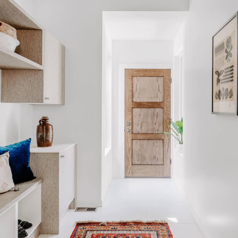 A narrow white room with wooden cabinetry and door