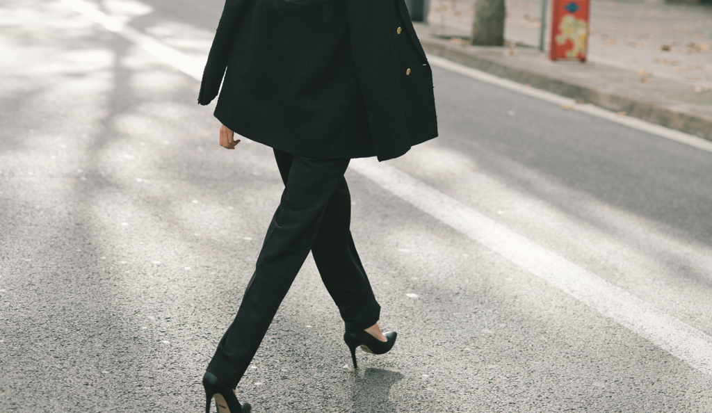A woman in black crossing the road